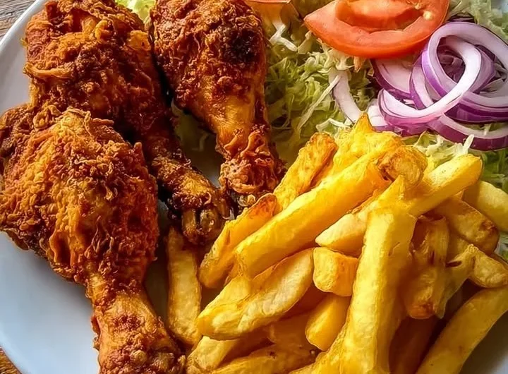 Crispy chicken drumsticks served with fries and salad on a plate