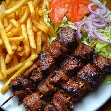Crispy grilled beef skewers with fries and garden salad on a serving plate