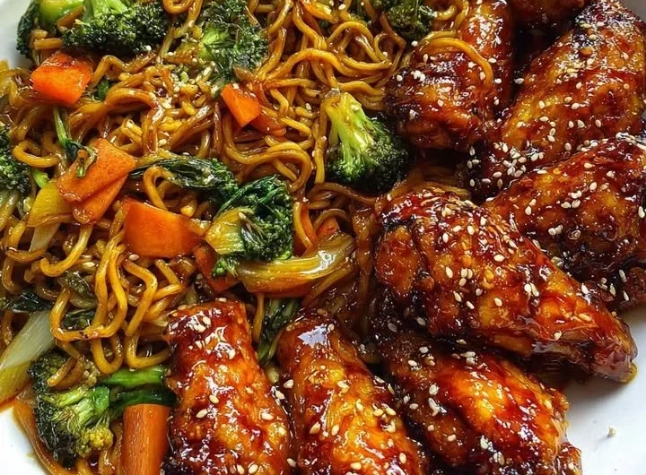 Crispy honey garlic chicken wings served with vegetable chow mein on a plate