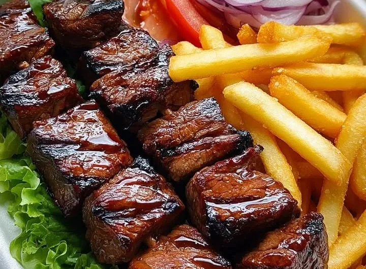 Grilled steak skewers served with crispy fries and a fresh side salad.
