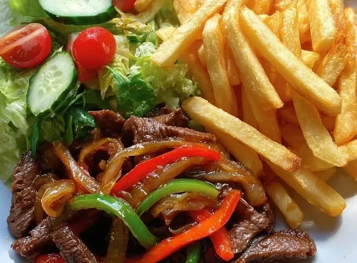 Pepper steak stir-fry with crispy fries and garden salad on a plate