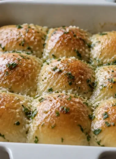Freshly baked garlic butter bread rolls served warm on a wooden table.